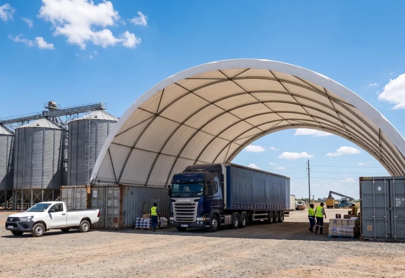 Grain trucks and workers beneath a large arched storage shelter.